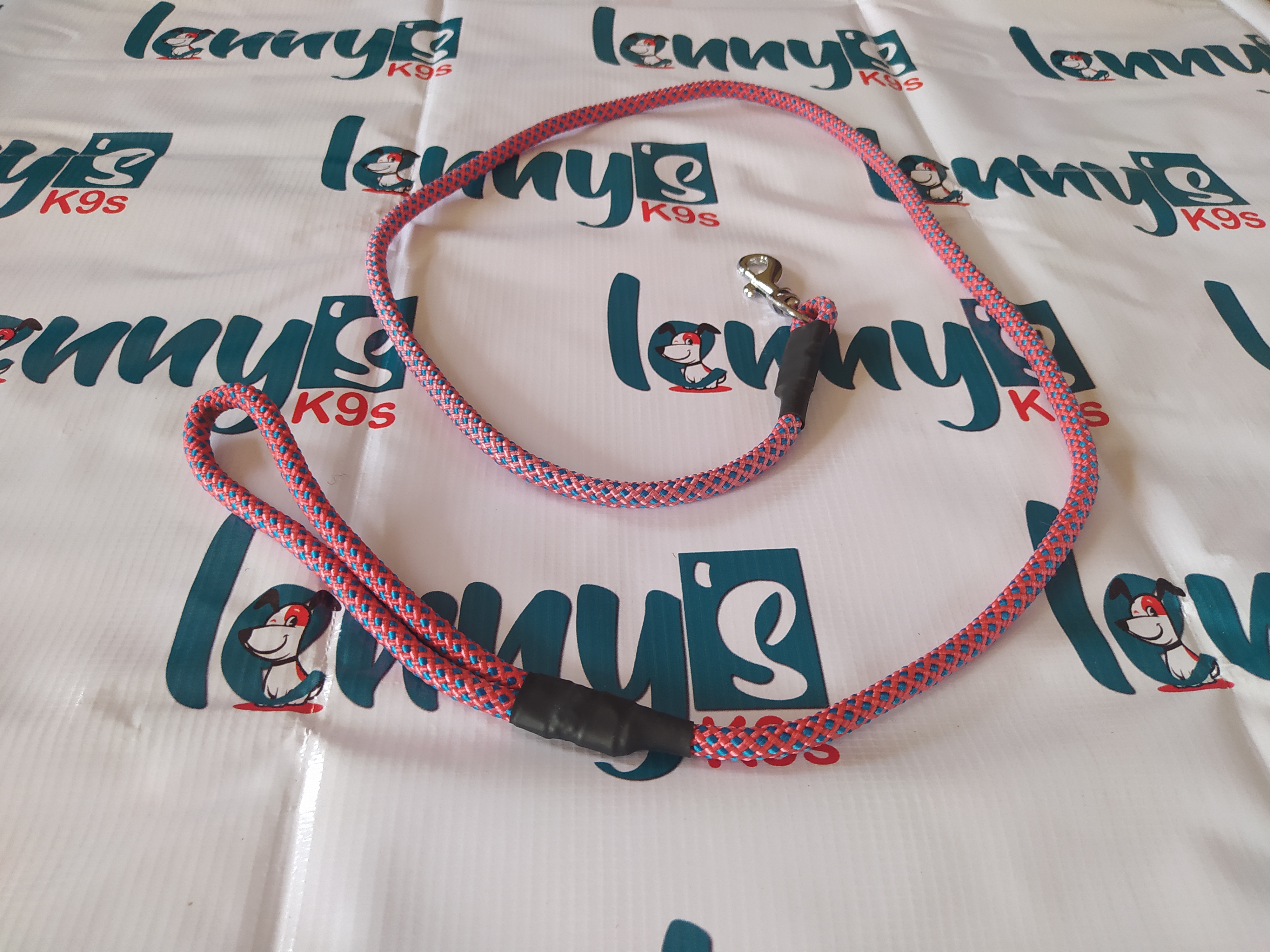 Pink and black braided rope dog leash with metal clip.